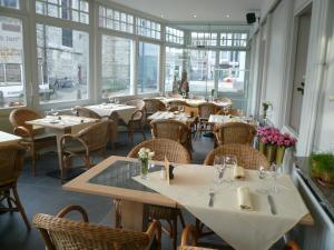 un restaurant avec des tables, des chaises et des fenêtres dans l'établissement Hotel La Barakka, à Lokeren