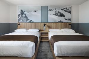 two beds in a room with snow covered mountains at The Approach Hotel in Panorama