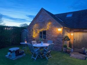 een patio met een tafel en stoelen in de tuin bij Holly Cottage The Studio in Hinstock