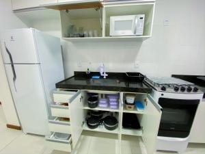 una cucina con piano cottura bianco e frigorifero di Férias em Família, Aconchego e Privacidade 209 a Cabo Frio