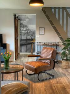 a living room with a chair and a staircase at Vakantiehuis Bed en Breakfast in de Tuin in Beilen