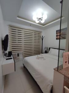 a bedroom with a large white bed and a television at Birch Tower by Tristoff in Manila