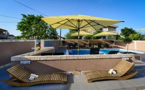 two wooden benches sitting next to a pool with an umbrella at Apartments Julijana 2 in Privlaka