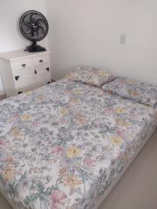 1 cama con edredón de flores en un dormitorio en Apto Centro Bertioga, en Bertioga