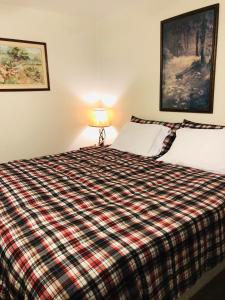 a bedroom with a bed with a plaid blanket at Black Hills Motel at Quail's Crossing in Hill City