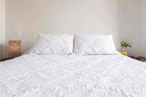 Una cama blanca con dos almohadas encima. en Moderno apt. en Col Roma, en Ciudad de México