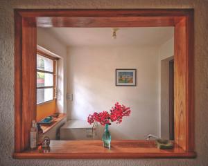 a mirror on a counter with a vase of flowers at HERMOSO ALOJAMIENTO TEMPORARIO KAYA in Villa Giardino