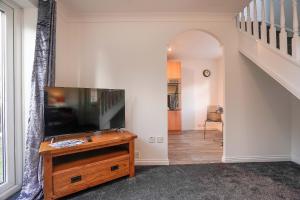a living room with a flat screen tv on a wooden stand at Victoria Gardens in Colchester