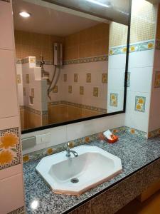 a bathroom with a sink and a large mirror at โรงแรมมูนแอนด์ซัน Moon and Sun Hotel in Chiang Rai
