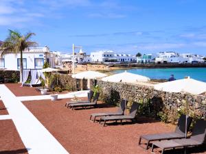 eine Gruppe von Stühlen und Sonnenschirmen an einem Strand in der Unterkunft La Graciosa Camelia Beach Vistas Mar in Caleta de Sebo