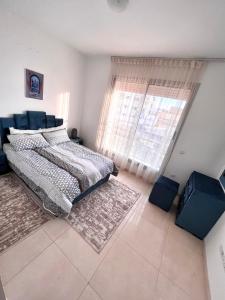um quarto com uma cama e uma grande janela em The blue pearl-Sensational beach apartment in Aourir em Agadir
