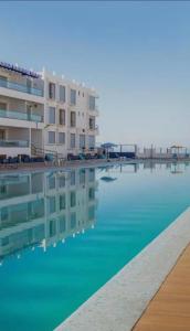 una gran piscina de agua frente a un edificio en The blue pearl-Sensational beach apartment in Aourir en Agadir