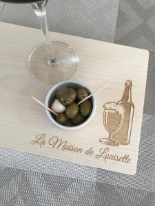 a wooden tray with a bowl of olives and a bottle of wine at La Maison de Louisette in Le Faouët