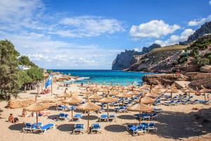 a beach with many chairs and umbrellas and the ocean at Villa Fonto in Pollença