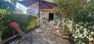 a patio with a table and chairs and an umbrella at Nice studio with terrace near the sea in Saint-Mandrier-sur-Mer +3 photos