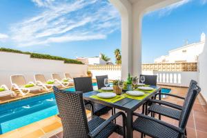 un patio con tavolo, sedie e piscina di Sa Luna ad Arenal d'en Castell