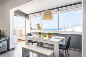 uma sala de jantar branca com uma mesa e cadeiras brancas em Sa Luna em Arenal d'en Castell