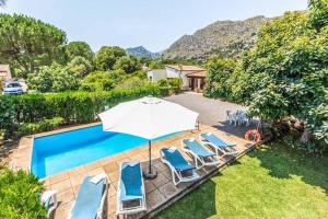 a swimming pool with chairs and an umbrella at Villa Rosita in Pollença