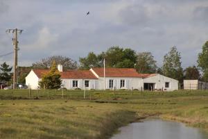 a white house in a field next to a river at L ETANG DES VACANCES Maison de charme au cœur des marais pour 6pers in Bouin