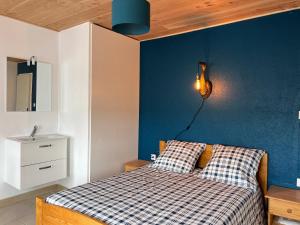 a bedroom with a bed with a blue wall at L ETANG DES VACANCES Maison de charme au cœur des marais pour 6pers in Bouin