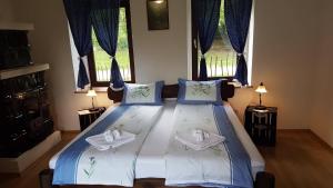 1 Schlafzimmer mit einem Bett mit blauer Bettwäsche und 2 Fenstern in der Unterkunft Zselic Szíve Parasztház in Simonfa