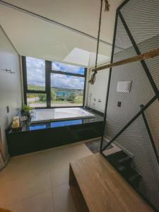 ein großes Bad mit einer Badewanne und einem großen Fenster in der Unterkunft Tiny House Cambará in Cambará