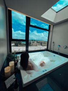 zwei Personen in einer Badewanne mit einem großen Fenster in der Unterkunft Tiny House Cambará in Cambará