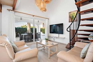 a living room with white furniture and a spiral staircase at Villa Elizabet in Cala en Forcat