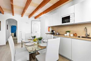 a kitchen and dining room with a glass table and white chairs at Villa Elizabet in Cala en Forcat