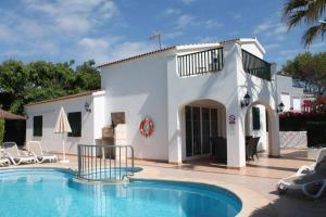 a villa with a swimming pool in front of a house at Villa Elizabet in Cala en Forcat