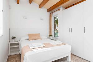 a white bedroom with a bed and a window at Villa Elizabet in Cala en Forcat +18 photos