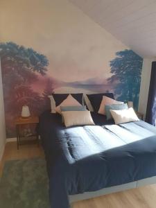 a bedroom with a blue bed with a painting on the wall at La maison des galeries classé 4 étoiles in Fécamp