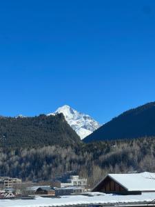 Une montagne enneigée au loin avec une ville dans l'établissement Galash-R, à Mestia