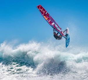 un hombre volando por el aire mientras montaba una ola en una tabla de surf en Charmant petit logement à 2 km (2 min) de la plage, en Belgodère