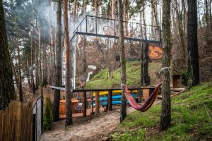 ein Zimmer mit einer Hängematte im Wald mit einem Wandbild in der Unterkunft Nad Narvią - dom na drzewie in Serock