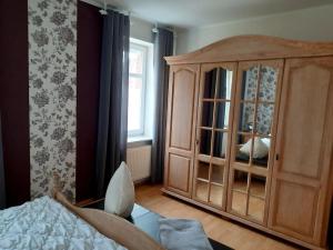 a bedroom with a large wooden cabinet next to a window at Urlaubsdomizil Norden/Norddeich, mit Garten in Norden