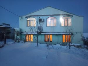 a house with its lights on in the snow at Orchard in Quba