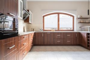 a kitchen with wooden cabinets and a large window at Apartamenty witów in Witów