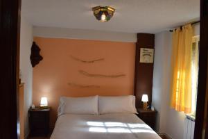 a bedroom with a white bed with twoisions on the wall at La Rocalla del Tiétar in Sotillo de la Adrada