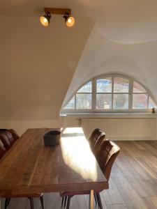 a dining room with a wooden table and a large window at Ferienwohnung Haus Ossenkopp in Dümmer