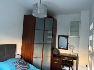 1 dormitorio con cama, escritorio y espejo en Apartament przy Parku Centralnym, en Gdynia