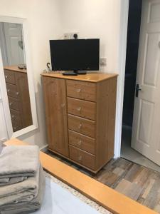 a television on a dresser in a room with a door at Hideaway Cabin for two on edge of New Forest in Hinton