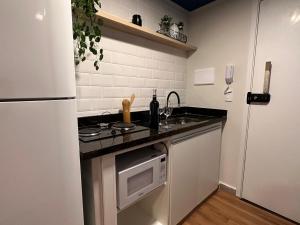 uma pequena cozinha com frigorífico e micro-ondas em Apê Bela Vista Major em São Paulo