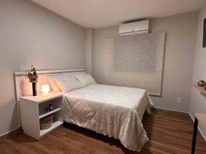 um pequeno quarto com uma cama branca e uma janela em Apê Bela Vista Major em São Paulo