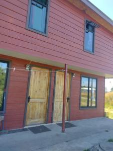 zwei Türen auf der Seite eines roten Gebäudes in der Unterkunft Departamento Rayen Karu in Puerto Montt