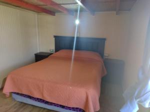 ein Schlafzimmer mit einem Bett mit einer orangefarbenen Bettdecke in der Unterkunft Departamento Rayen Karu in Puerto Montt