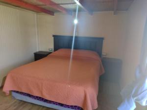 a bedroom with a bed with a orange comforter at Departamento Rayen Karu in Puerto Montt