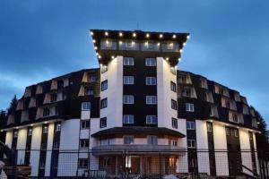 un grand bâtiment avec des lumières au sommet dans l'établissement Sunčana Planina Kopaonik, à Kopaonik