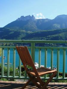 una silla de madera sentada en un balcón con vistas al agua en Le pavillon du lac en Duingt