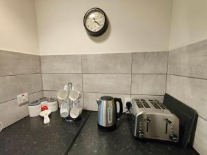 a kitchen counter with a toaster and a clock on a wall at Penlon Farm Cottage in Cardigan